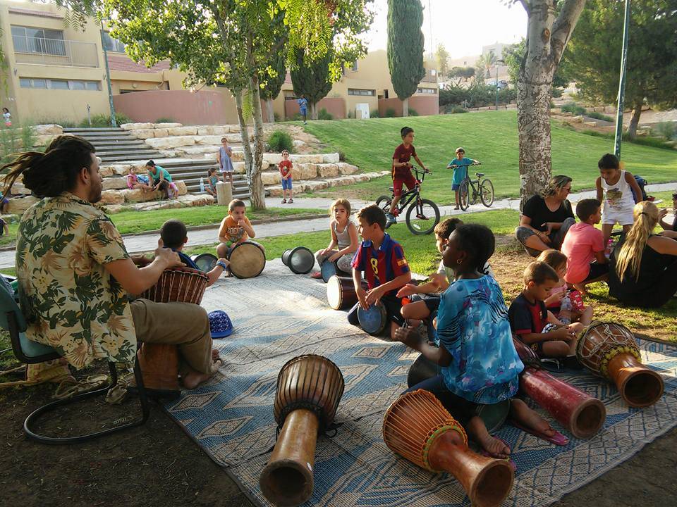 ילדים יושבים במעגל עם מדריך ומנגנים בטארבוקה